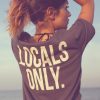 Ragazza in spiaggia con t-shirt grigia con stampa Locals Only sulla schiena
